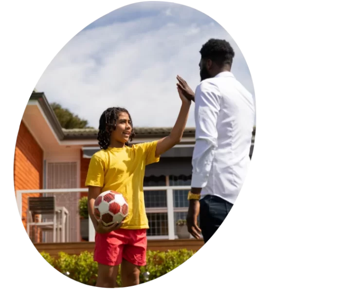 A child holding a soccer ball and an adult high-fived each other